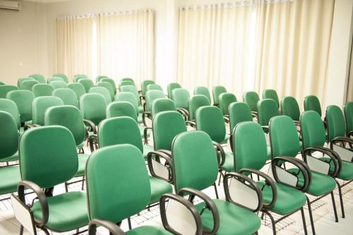 an empty room with green chairs and curtains at Italian Palace Hotel in Palmas