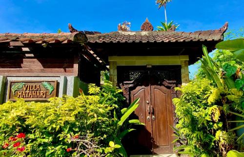 a building with a wooden door in a garden at Tropical Villa Matahari - 500sqm private Garden Retreat with large Pool! in Uluwatu