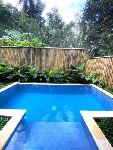a swimming pool in front of a wooden fence at Hidden Bamboo Village in Selat