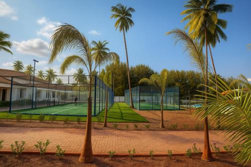 a tennis court with palm trees in the background at JAZ Elite Aurora in Michamvi