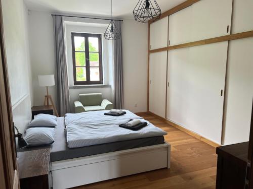 a bedroom with a bed with a chair and a window at Fara Rejštejn in RejÅ¡tejn
