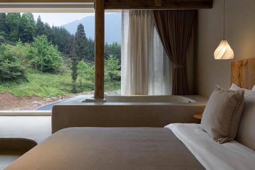 a bedroom with a bed and a large window with a tub at Twilight Cloud Spring Tree Private Hot Spring Homestay Bifengxia Panda Base Store in Ya'an