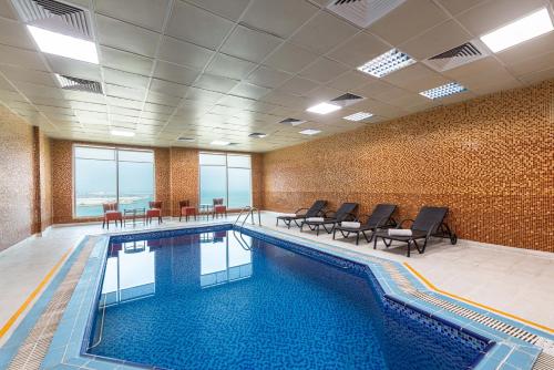 a large swimming pool in a building with chairs at Razana Hotel Al Jubail in Al Jubayl