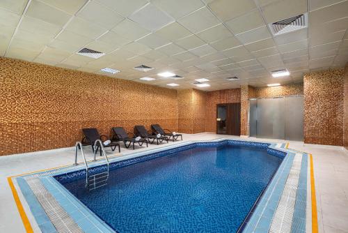 a room with a pool with chairs and a room with at Razana Hotel Al Jubail in Al Jubayl