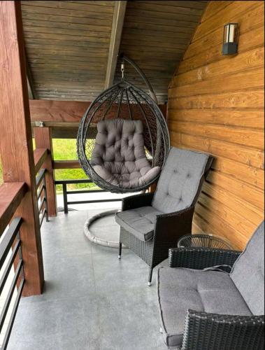 a porch with a swing and a chair and a couch at Cottage MiniHouse in Kozevo