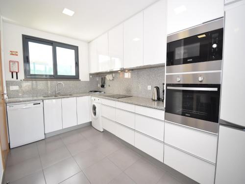 una cucina bianca con armadietti e elettrodomestici bianchi di Family Villa with Terrace and Pool a Foz do Arelho