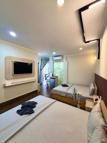 a hotel room with two beds and a flat screen tv at Homestay The Sunset in Phan Thiet