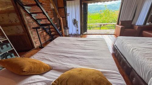 two beds sitting in a room with a window at DeeTorJai FarmStay Nan ดีต่อใจ ฟาร์มสเตย์ น่าน โดยเจ้าของ in Ban Klang