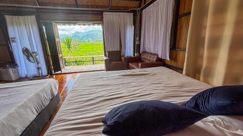 a bedroom with two beds and a window with a view at DeeTorJai FarmStay Nan ดีต่อใจ ฟาร์มสเตย์ น่าน โดยเจ้าของ in Ban Klang