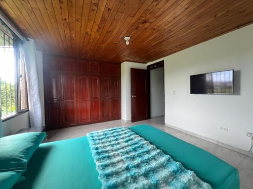 a bedroom with a green bed with a wooden ceiling at Hostal Comunidad HBT in Pereira