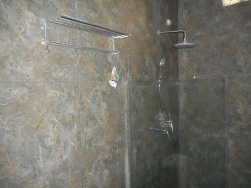 a bathroom with a shower with a stone wall at Besakih Bonny Homestay in Besakih