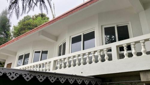 a white house with a white balcony at Lemos Cafe and Homestay in Kurseong