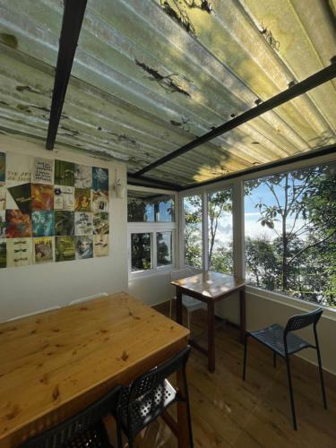 a room with a table and chairs and windows at Lemos Cafe and Homestay in Kurseong