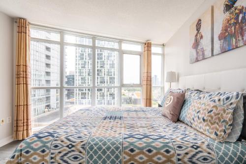 a bedroom with a bed and a large window at Corner 2 Bedroom 2 Bathroom Condo Balcony Iceboat Terrace Downtown Toronto in Toronto