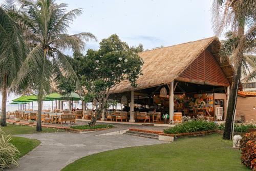 a restaurant with tables and chairs and palm trees at Palm Garden Beach Resort & Spa in Hoi An