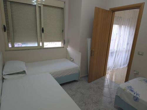 Un dormitorio pequeño con dos camas y una ventana. en Casa di Mare, en Vlorë