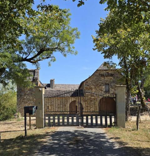 an old brick building with a gate and a fence at Ferme du XVIIe siècle restaurée 120 m2 in Goutrens