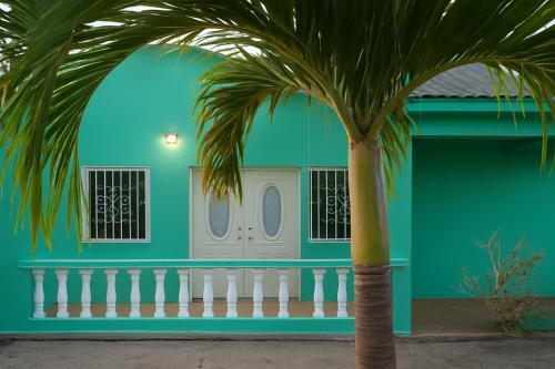 a green house with a palm tree in front of it at Tropical Breeze Grenada in Westerhall Land Settlement