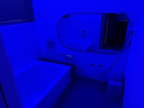 a bathroom with a mirror and a blue light at 一棟貸し宿 ｍａｉｃｃａ in Numazu