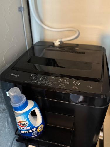 a microwave oven with a bottle of water next to it at 一棟貸し宿 ｍａｉｃｃａ in Numazu