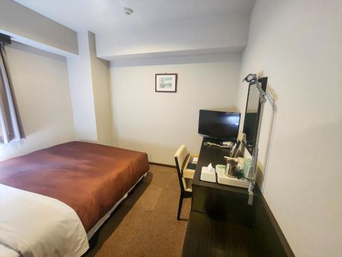 a hotel room with a bed and a desk with a television at ホテルアイシス掛川 in Kakegawa