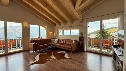 a living room with a couch and large windows at Bergquelle Dachwohnung in Bettmeralp
