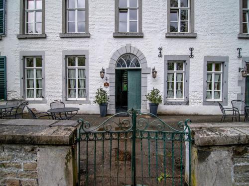 a white building with a green door and a fence at Castle Apartment Aywaille near River Amblève in Aywaille