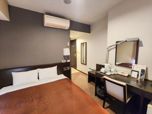 a bedroom with a bed and a desk and a mirror at ホテルアイシス掛川 in Kakegawa