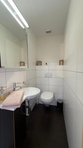 a white bathroom with a toilet and a sink at Bergquelle Dachwohnung in Bettmeralp