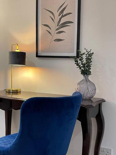 a blue chair sitting next to a desk with a vase at Modern One-bed Flat in Armley in Leeds
