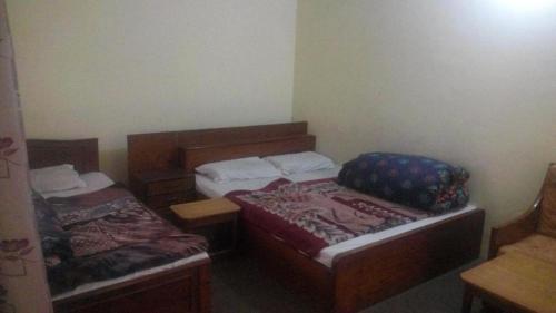 a small room with two beds in a room at Tanveer Hotel in Dargai