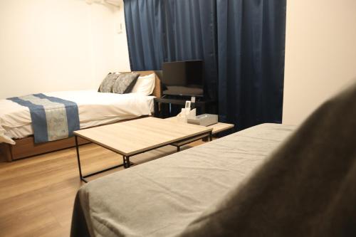 a room with two beds and a table with a tv at Ra premier K Osaka NAMBA Shinsaibashi USJ Shinimamiya Hanazonocyo in Osaka