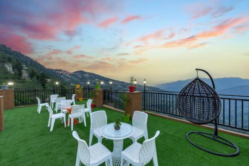 a balcony with tables and chairs and a view of the mountains at The Charvi Retreat Hospitality l Stargaze Café l I Open Air Multi Cuisine Restaurant l Balaju Banquet Hall l Sky Night Bonfire l Free Wi-Fi Connectivity l Kufri by Exotic Stays in Kūfrī