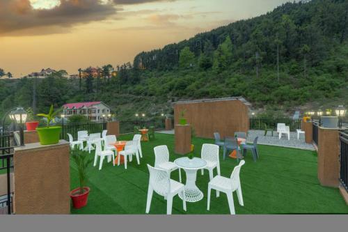 a group of white chairs and tables on a balcony at The Charvi Retreat Hospitality l Stargaze Café l I Open Air Multi Cuisine Restaurant l Balaju Banquet Hall l Sky Night Bonfire l Free Wi-Fi Connectivity l Kufri by Exotic Stays in Kūfrī