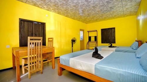 a bedroom with two beds and a desk and yellow walls at Mountain View Tranquil Eco Remote Lodge in Sigiriya