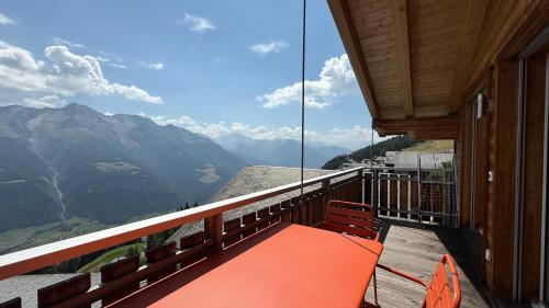 an orange bench on a balcony with a view of mountains at Bergquelle Dachwohnung in Bettmeralp