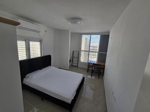 a bedroom with a bed and a table and windows at GK Apartments Urban Comfort Balfour in Bat Yam