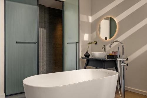 a white bath tub in a bathroom with a mirror at Caro Premium Danang Hotel in Da Nang