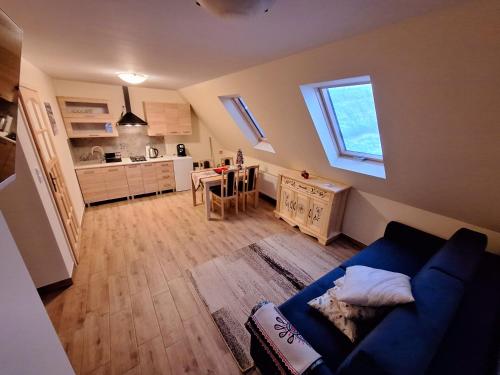 a living room with a blue couch and a kitchen at U KUCHTÓW Apartamenty i Wypożyczalnia Sprzętu Sportowego in Białka Tatrzanska
