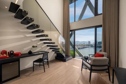 a staircase in a living room with a desk and chairs at Caro Premium Danang Hotel in Da Nang