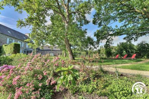 a garden with pink flowers and a tree and chairs at Le jardin de quercus in Bazouges-la-Pérouse