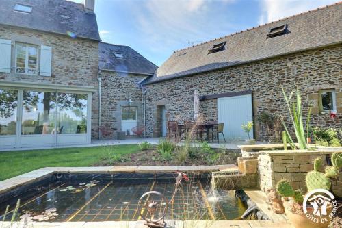 a brick house with a pond in the yard at Le jardin de quercus in Bazouges-la-Pérouse