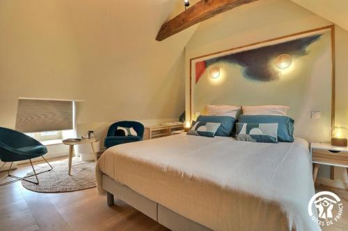 a bedroom with a large bed with blue pillows at Le jardin de quercus in Bazouges-la-Pérouse