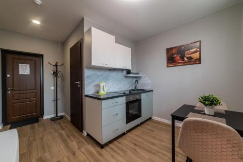 a kitchen with white cabinets and a table with chairs at Svečių namai Imperija in Šiauliai