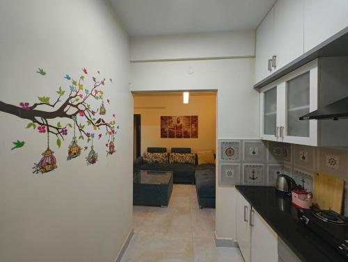 a kitchen with a tree mural on the wall at M's Cozy Unwind - Hazel in Bengaluru