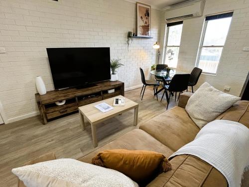 a living room with a couch and a flat screen tv at Stylish 3 Bedroom Apartment - South Hedland in South Hedland
