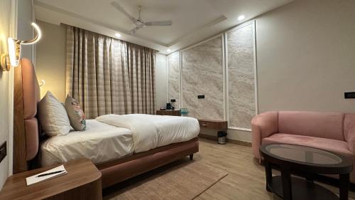 a bedroom with a bed and a chair and a table at Sanguine Varanasi in Varanasi