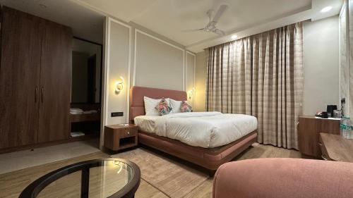 a bedroom with a bed and a table and a chair at Sanguine Varanasi in Varanasi