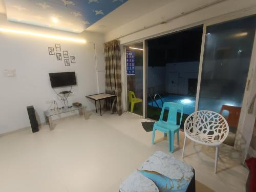 a living room with a tv and a couch and chairs at Sky line villa, Lonavla in Lonavala