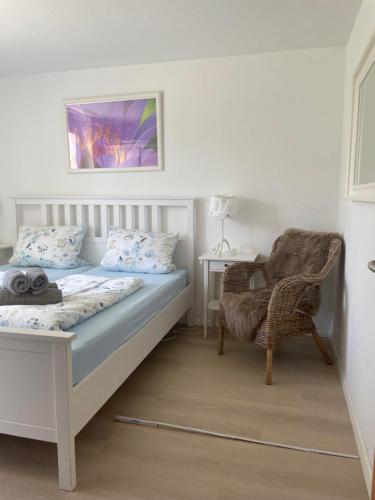 a bedroom with a white bed and a chair at Ferienwohnung Seewind in Überlingen
